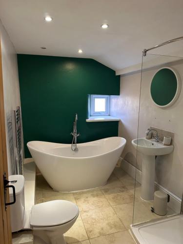 a bathroom with a tub and a toilet and a green wall at Sugar Plum Cottage in Conisbrough