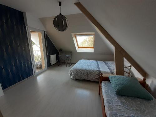 een slaapkamer op zolder met 2 bedden en een trap bij Jolie maison dans nature paisible, Côte de Granit Rose proche plage. in Trébeurden