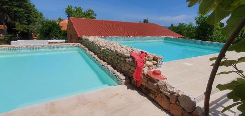a swimming pool with a stone wall and a red roof at Quinta da Bizelga Cottages in Tomar
