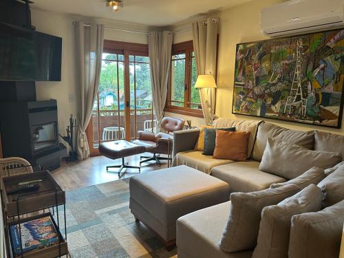 een woonkamer met een bank en een tafel bij Duplex 3 suites com Jacuzzi e Lareira Apto Sattva Plaza in Gramado