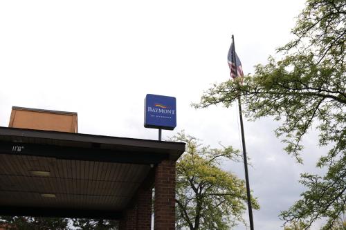a sign on top of a building with a flag at Baymont by Wyndham Flint Airport North in Flint