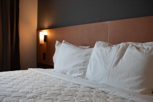 a bed with white pillows and a wooden headboard at Comfort Hotel Presidente Prudente in Presidente Prudente