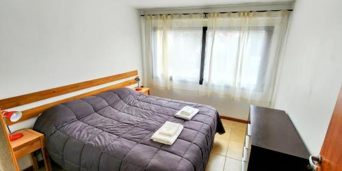 1 dormitorio con cama morada y ventana en Belgrano 555 en San Martín de los Andes