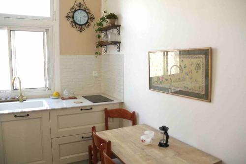 a kitchen with a table and a sink and a clock at Lily’s house in Haifa