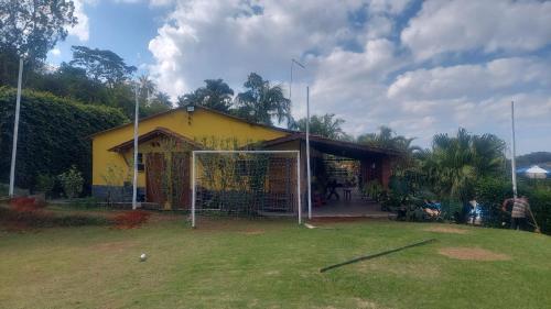 une maison jaune avec un but de football dans la cour dans l'établissement Chácara Recanto do Sol, à Mogi das Cruzes