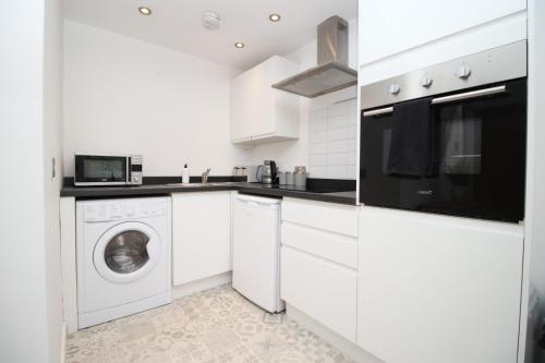 a white kitchen with a washer and dryer at Central Mumbles Apartment, Properties By O & G, Incredible Location, Sleeps 4! in The Mumbles