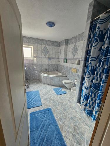 a bathroom with a tub and a toilet with blue mats at Stan Sana-Centar in Sanski most