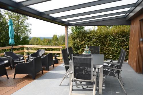 a patio with black chairs and tables and a roof at Holiday Home Mooi-Gemmenich in Plombières