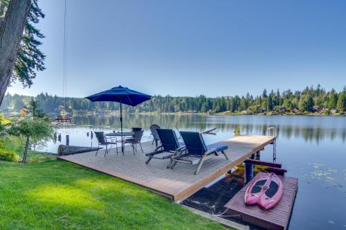 a dock with chairs and an umbrella on a lake at Lakefront Snohomish Cottage with Private Dock! in Snohomish