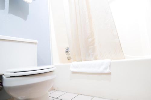 a white bathroom with a toilet and a shower at Baymont by Wyndham Flint Airport North in Flint