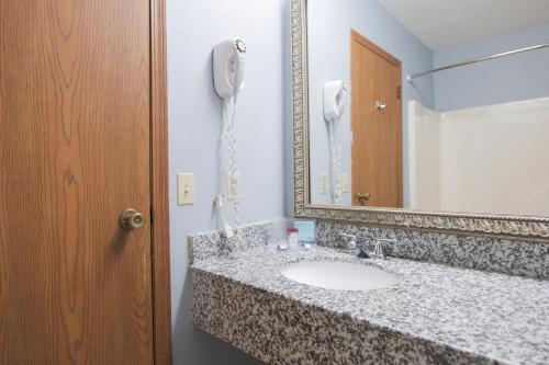 a bathroom with a sink with a phone on the wall at Baymont by Wyndham Flint Airport North in Flint
