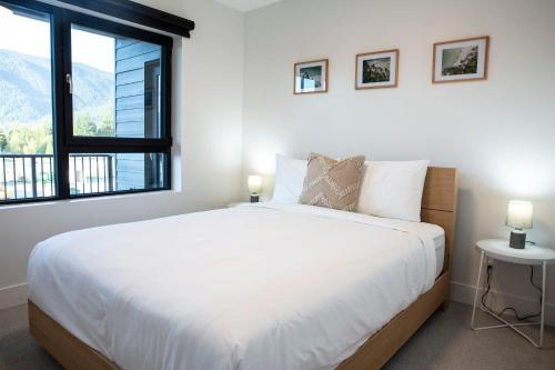 um quarto branco com uma cama grande e uma janela em Revy Mountain Retreat em Revelstoke