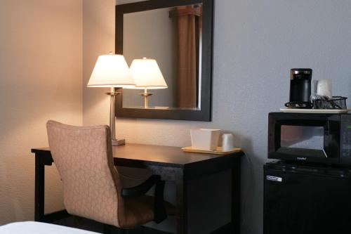 a desk in a hotel room with a chair and a mirror at Baymont by Wyndham Flint Airport North in Flint