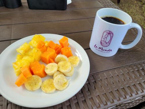 um prato de frutas em uma mesa ao lado de uma xícara de café em La Morada, una ventana al golfo - Hotel boutique em Monte Gordo