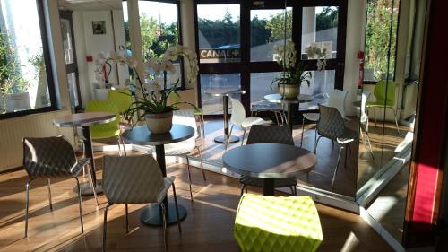 a restaurant with tables and chairs and windows at A&H PRIVILÈGE Lyon Est - Saint Priest Eurexpo in Saint-Priest