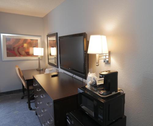 a hotel room with a desk with a television and a desk sidx sidx sidx sidx at Baymont by Wyndham Flint Airport North in Flint