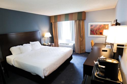 a hotel room with a bed and a window at Baymont by Wyndham Flint Airport North in Flint