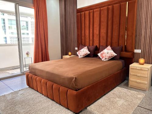 - une chambre avec un grand lit et une grande tête de lit en bois dans l'établissement Appartement la gare Rabat ville, à Rabat