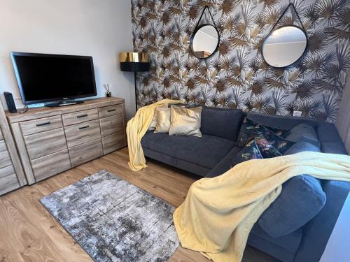 uma sala de estar com um sofá e uma televisão de ecrã plano em Aqua Zoo Arena Green Retkinia District em Łódź
