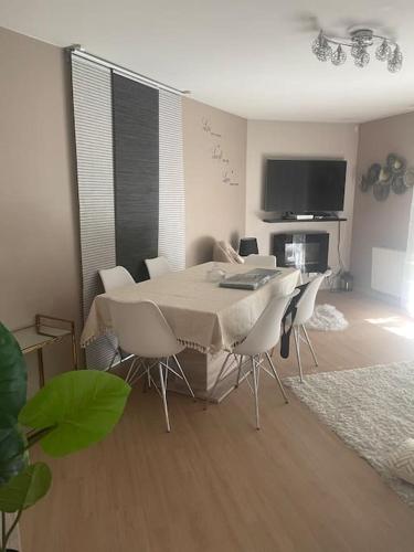 una sala da pranzo con tavolo, sedie e TV di Cosy appart proche du rer A et psa a Carrières-sous-Poissy