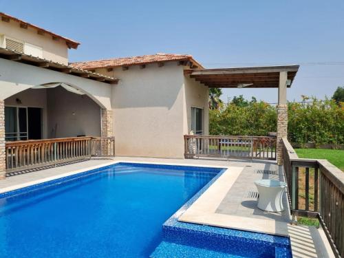 a swimming pool in front of a house at Villa with a pool in a beautiful garden in Tal Shaẖar