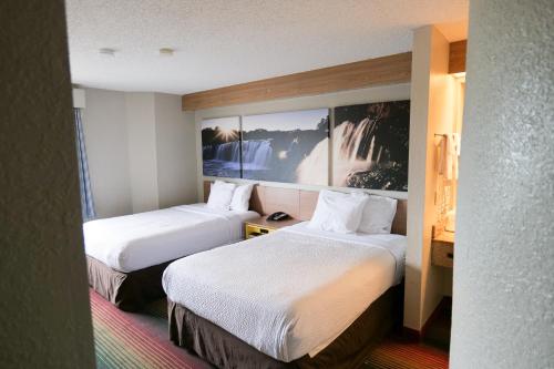 a hotel room with two beds in a room at Days Inn by Wyndham Flint/Bishop International Airport in Flint