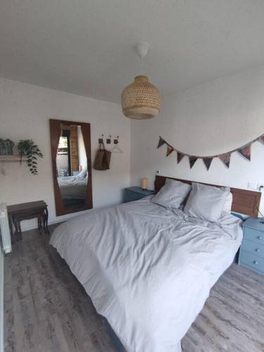 une chambre avec un grand lit blanc et un miroir dans l'établissement P'tit Cocon aux portes de Rouen, à Saint-Aubin-Epinay