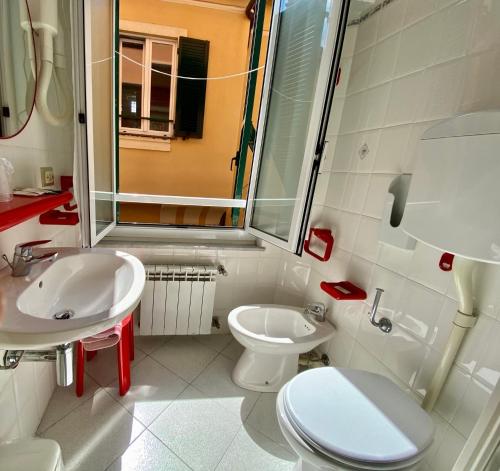 a white bathroom with a toilet and a sink at Hotel Alba Chiara in Finale Ligure