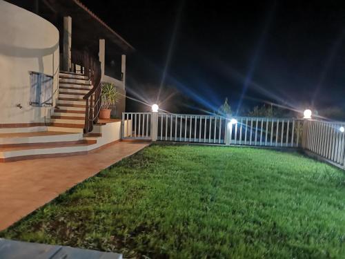 a house with a fence and a yard at night at Nel verde del Villaggio - Casetta Celeste in Gonnesa