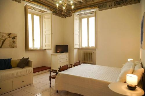a bedroom with a bed and a couch and windows at Il Carapace - Appartamento nel cuore di Foligno in Foligno