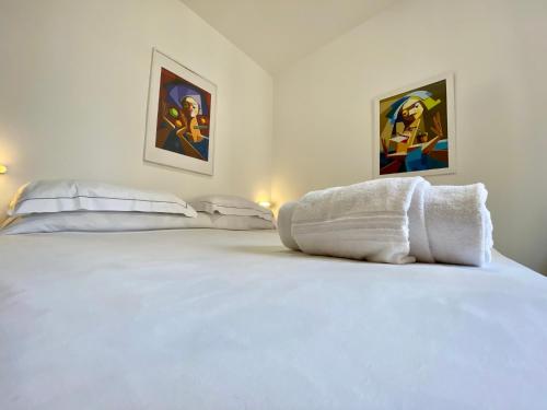 a bedroom with a white bed with two pictures on the wall at Hotel Alba Chiara in Finale Ligure