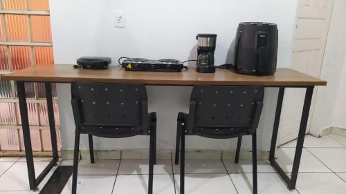 a wooden table with two chairs and a coffee maker on it at Casa Aconchegante in Marabá
