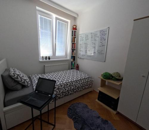 um pequeno quarto com uma cama e um computador portátil sobre uma mesa em Vienna: Cozy 2-Room Apt. (U3 - Schweglerstrasse) em Viena
