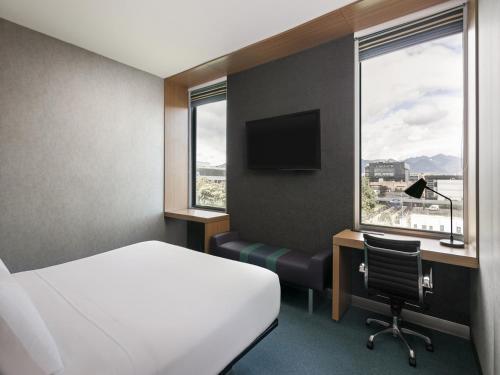 a hotel room with a bed and a desk and window at Aloft Bogotá Airport in Bogotá