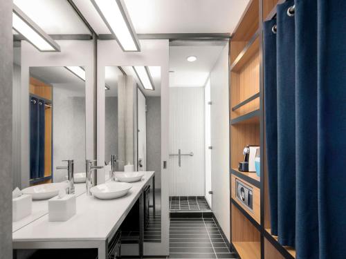 a bathroom with three sinks and a row of mirrors at Aloft Bogotá Airport in Bogotá