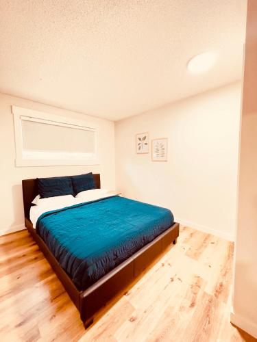 Entire 3 bedroom house في إيدمونتون: غرفة نوم مع سرير وبطانية زرقاء