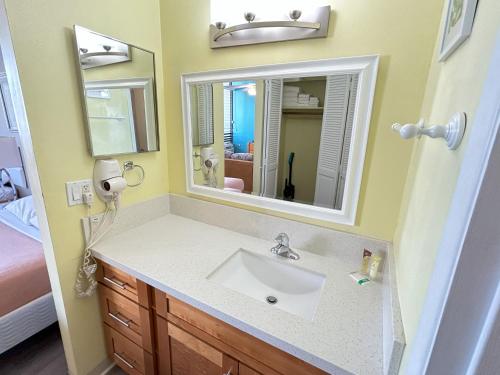 La salle de bains est pourvue d'un lavabo et d'un miroir. dans l'établissement Royal Kuhio 1704 - Spacious Studio with Stunning Mountain Views in the Heart of Waikiki!, à Honolulu
