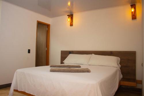 a bedroom with a white bed with two pillows on it at Hostería El Sendero - Cocorná in Cocorná
