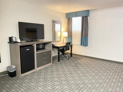 a hotel room with a television and a desk with a computer at Days Inn & Suites by Wyndham Spokane in Spokane