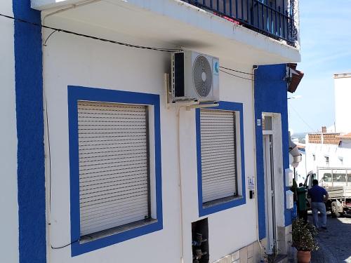a blue and white building with three windows and a fan at Casa da laranjeira in Montargil