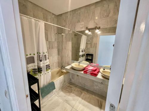 uma casa de banho com 2 lavatórios, uma banheira e um espelho. em El Coloso de SteraM Flats Benalmádena em Benalmádena