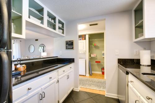 una cocina con armarios blancos y encimeras negras en Pinehurst Condo Rental Near Golf with Pool Access!, en Pinehurst