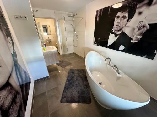 La salle de bains est pourvue d'une baignoire et d'une affiche d'un homme. dans l'établissement St.Barbara Trier, à Trèves