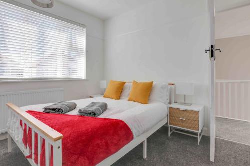 a white bedroom with a large bed with orange pillows at Grove House Southend on Sea in Southend-on-Sea