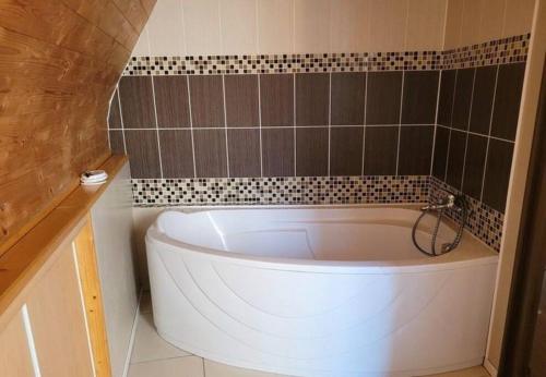 a white tub in a bathroom with a tiled wall at Appartement au pied du château in Montbéliard