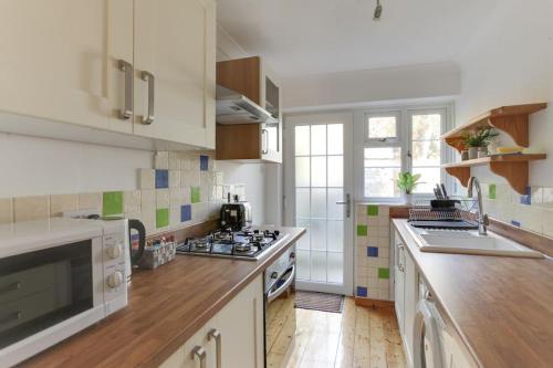 a kitchen with a sink and a stove top oven at Roman Cottage Chelmsford in Chelmsford