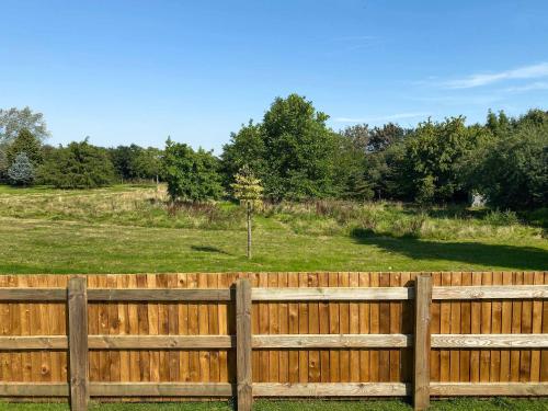 a wooden fence with a field in the background at Millers Rest in Hickling