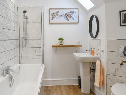 a white bathroom with a shower and a sink at West Lodge in Sewerby