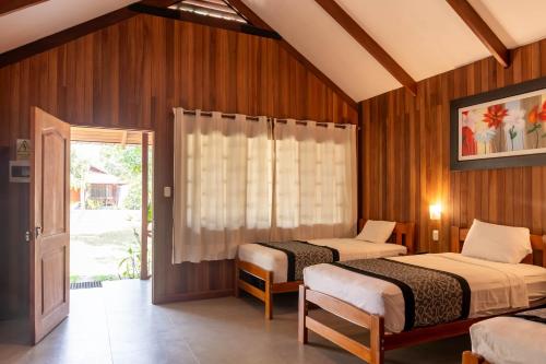 two beds in a room with wooden walls at WAKAYA ECOLODGE in Pucallpa