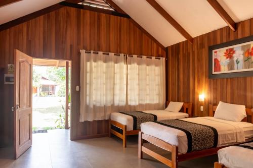 2 camas en una habitación con paredes de madera en WAKAYA ECOLODGE, en Pucallpa